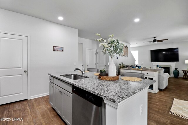 kitchen featuring dishwasher, a sink, a ceiling fan, dark wood finished floors, and light stone countertops