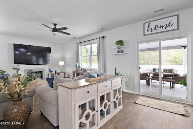 living area with visible vents, ceiling fan, wood finished floors, and baseboards
