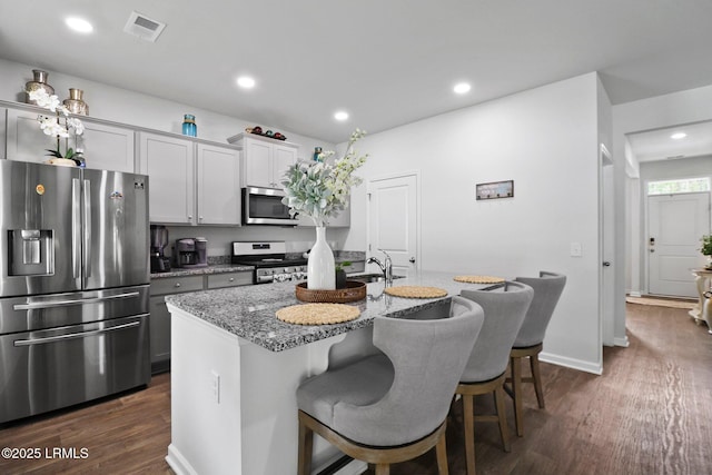 kitchen featuring dark wood-style floors, visible vents, a breakfast bar area, and appliances with stainless steel finishes