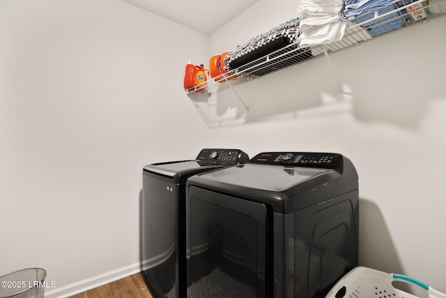 clothes washing area featuring baseboards, wood finished floors, separate washer and dryer, and laundry area