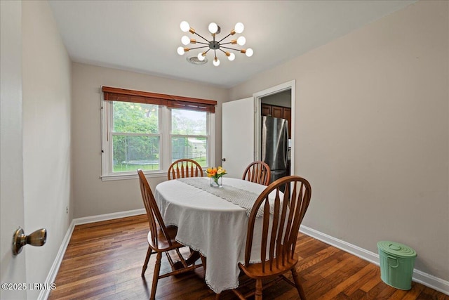 dining room featuring a chandelier, baseboards, and dark wood-type flooring