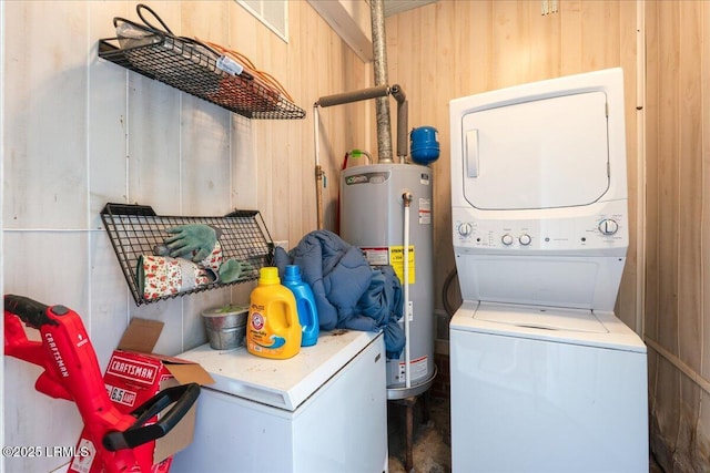 washroom featuring stacked washing machine and dryer, gas water heater, and wooden walls