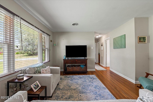 living area with plenty of natural light, wood finished floors, and baseboards
