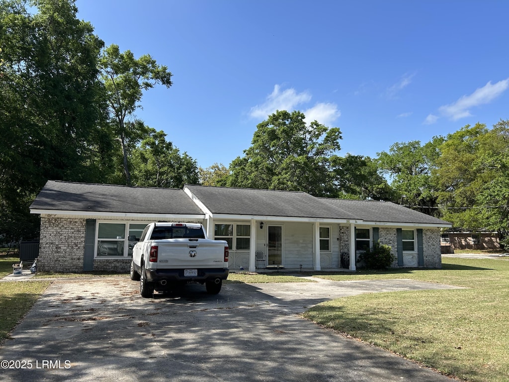 ranch-style home featuring brick siding, aphalt driveway, and a front lawn