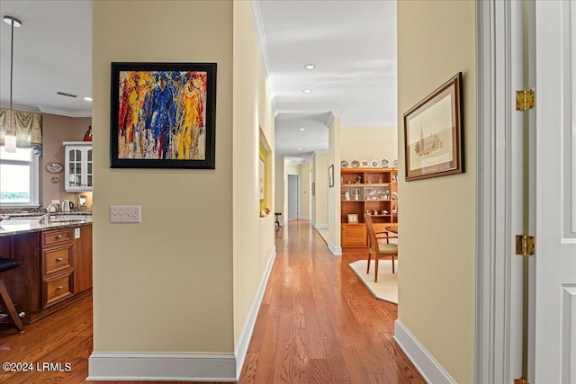 corridor featuring ornamental molding and light wood-type flooring