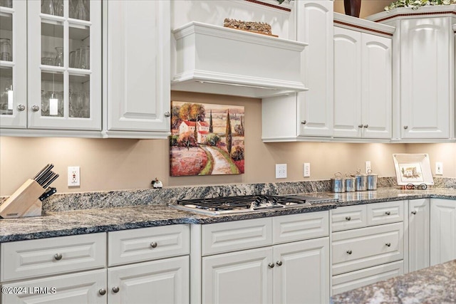 kitchen featuring stainless steel gas stovetop, white cabinetry, and dark stone counters