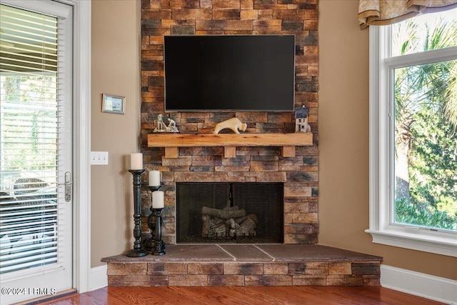 room details featuring a stone fireplace and wood-type flooring