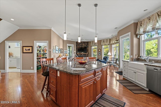 kitchen featuring sink, white cabinetry, stainless steel dishwasher, an island with sink, and dark stone counters