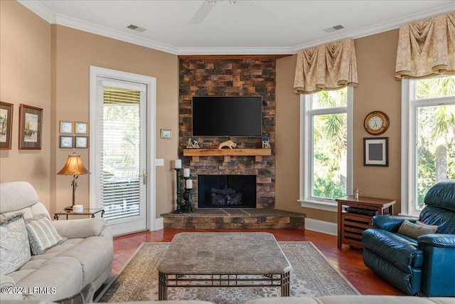 living room featuring crown molding, a stone fireplace, ceiling fan, and hardwood / wood-style flooring