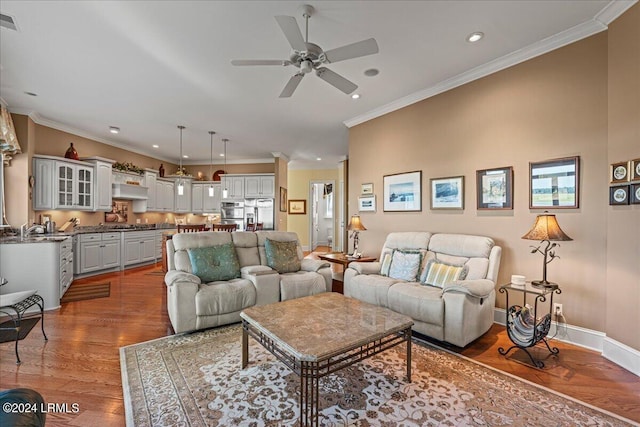 living room with ornamental molding, ceiling fan, and light wood-type flooring