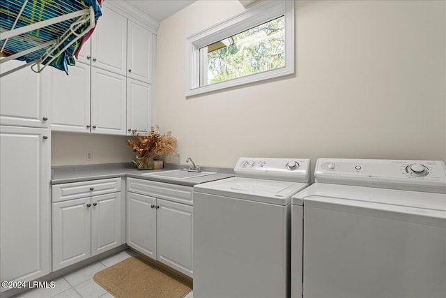 clothes washing area featuring cabinets, sink, light tile patterned floors, and washer and clothes dryer