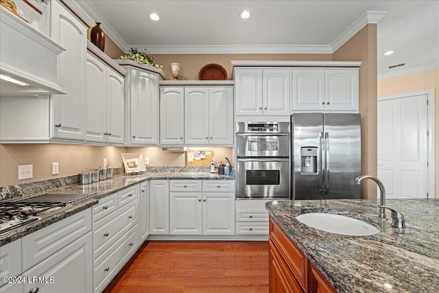 kitchen with white cabinetry, sink, stainless steel appliances, and dark stone countertops