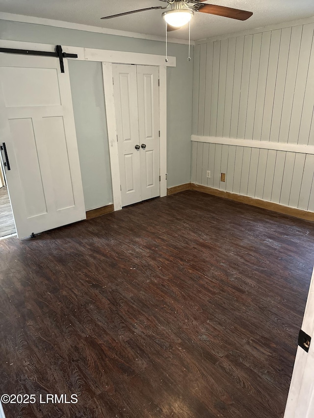 208 Squirrel Aly, Ridgeland, SC 29936 - unfurnished bedroom with dark wood finished floors, baseboards, a ceiling fan, and a barn door