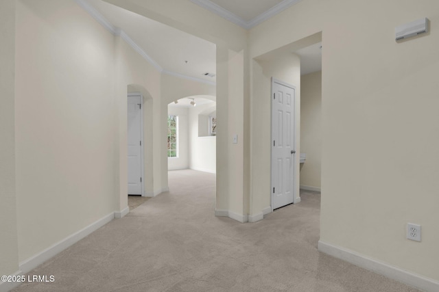 corridor featuring ornamental molding, arched walkways, and light carpet