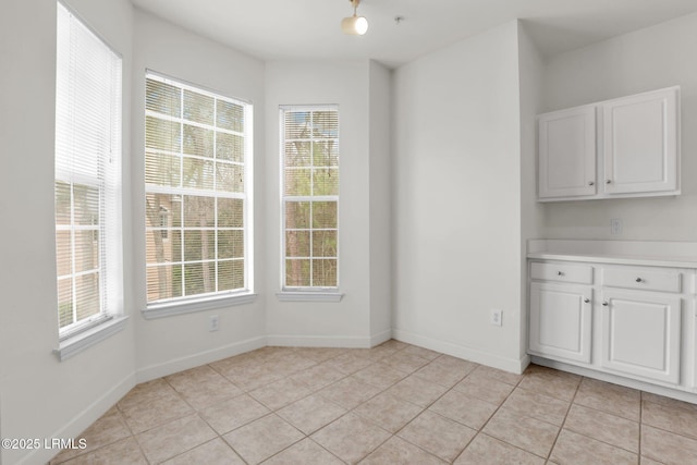 unfurnished dining area with baseboards and light tile patterned floors