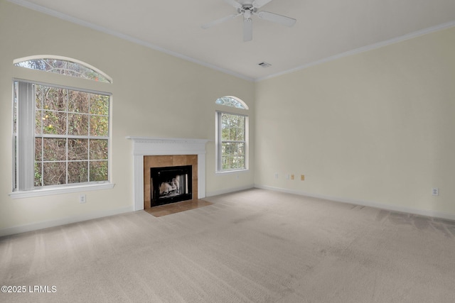 unfurnished living room featuring light carpet, baseboards, a tiled fireplace, ceiling fan, and crown molding