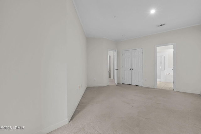 spare room with baseboards, visible vents, ornamental molding, and light colored carpet