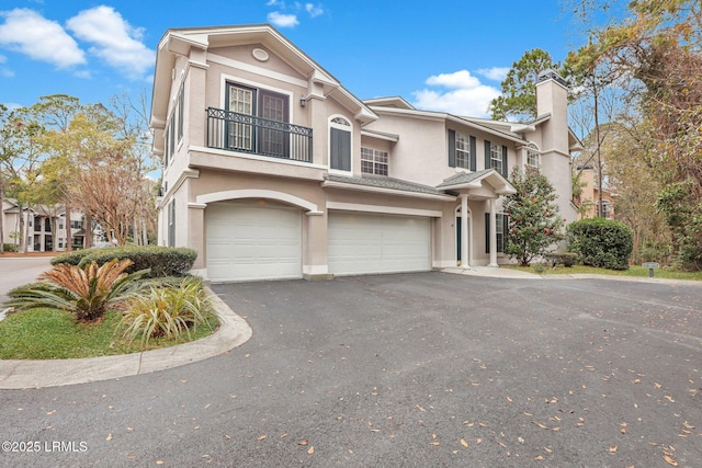 view of front of property featuring a garage, aphalt driveway, a chimney, and stucco siding