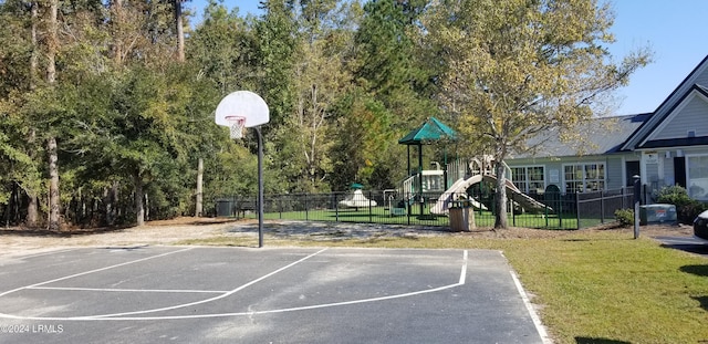 view of basketball court featuring a playground and a lawn