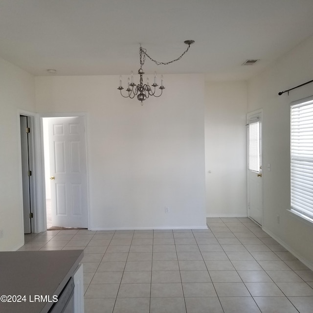 tiled empty room featuring a chandelier