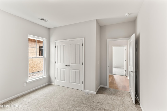 unfurnished bedroom featuring light carpet and a closet