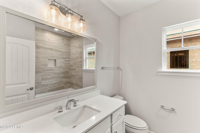 bathroom with vanity, tiled shower, and toilet