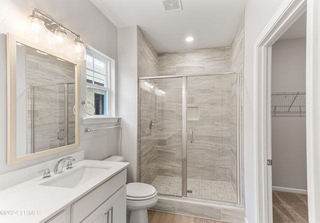 bathroom with vanity, toilet, and a shower with door