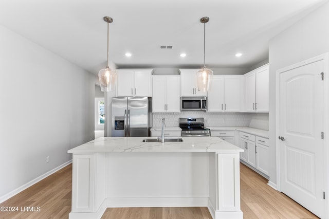 kitchen with appliances with stainless steel finishes, white cabinetry, sink, a kitchen island with sink, and light stone countertops