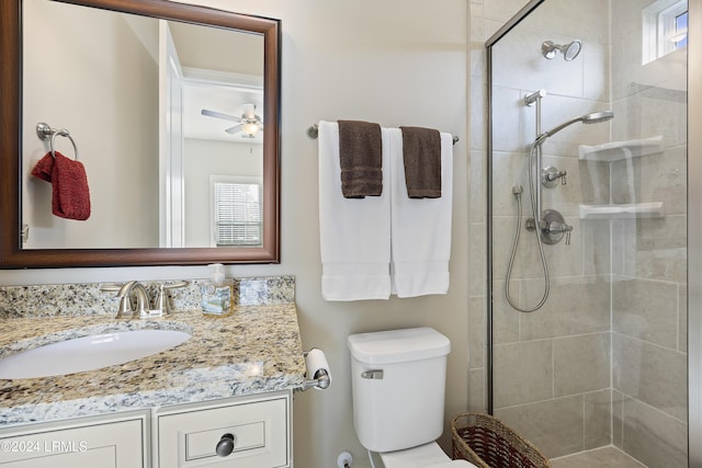 bathroom with a shower with door, vanity, ceiling fan, and toilet