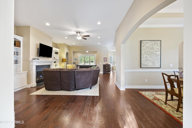 living room featuring ceiling fan, crown molding, dark hardwood / wood-style flooring, and built in shelves