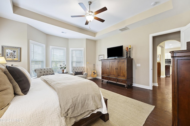 bedroom featuring ceiling fan, dark hardwood / wood-style floors, and a raised ceiling