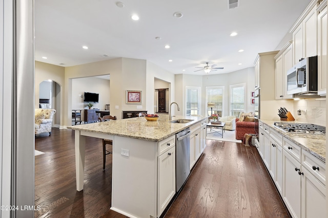 kitchen with an island with sink, sink, a breakfast bar area, stainless steel appliances, and dark wood-type flooring