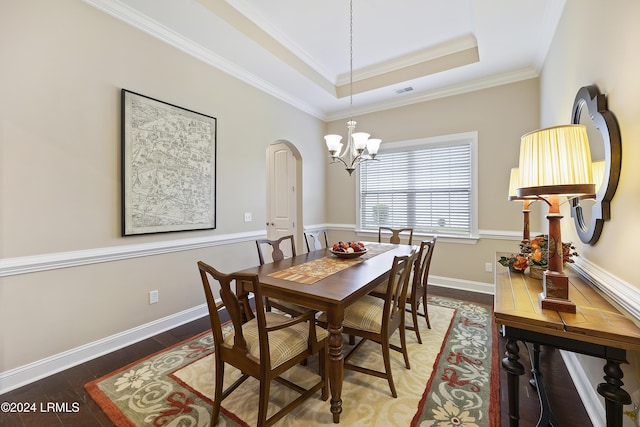 dining room featuring dark hardwood / wood-style flooring, crown molding, a tray ceiling, and a chandelier