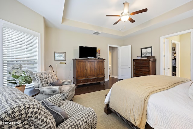 bedroom with hardwood / wood-style flooring, a raised ceiling, and ceiling fan