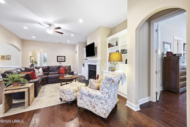 living room with dark hardwood / wood-style floors, ceiling fan, and built in shelves