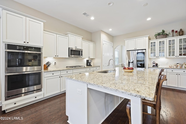 kitchen with sink, stainless steel appliances, an island with sink, and white cabinets