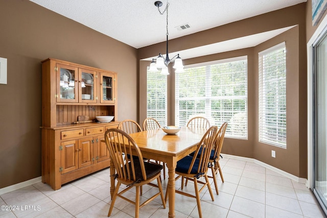 dining area featuring an inviting chandelier, light tile patterned floors, and a textured ceiling