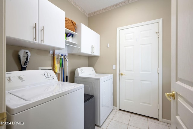 washroom featuring cabinets, light tile patterned floors, and washing machine and clothes dryer