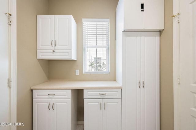 kitchen with white cabinetry, built in desk, and a wealth of natural light