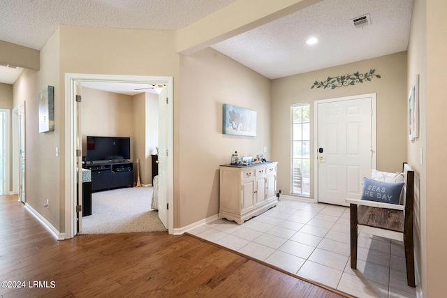 foyer entrance with light hardwood / wood-style flooring, beamed ceiling, and a textured ceiling