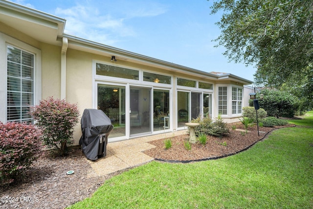 rear view of property featuring a sunroom and a lawn