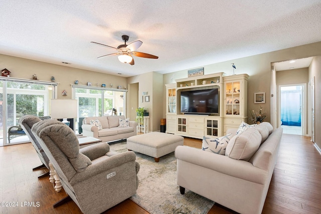 living room featuring ceiling fan, hardwood / wood-style floors, and a textured ceiling