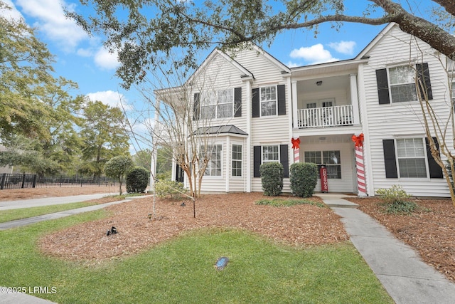 view of front facade with a front lawn and a balcony