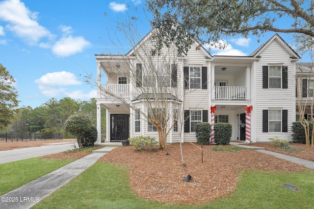 view of property featuring a balcony and a front lawn