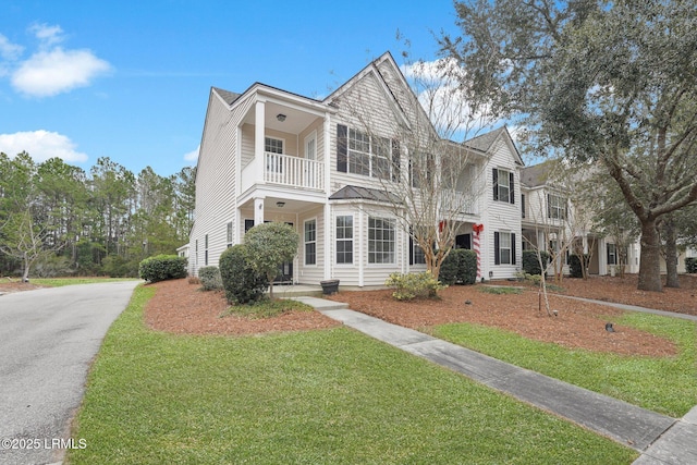 view of front of house with a balcony and a front yard