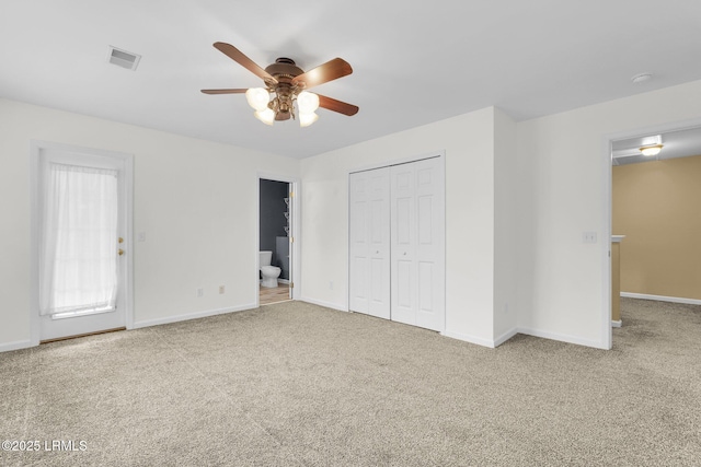 unfurnished bedroom with a closet, carpet flooring, ceiling fan, and ensuite bath