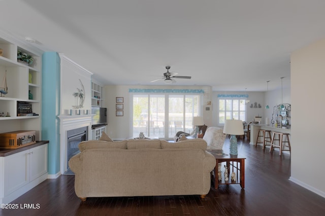 living room featuring dark wood-type flooring, ceiling fan, and built in shelves