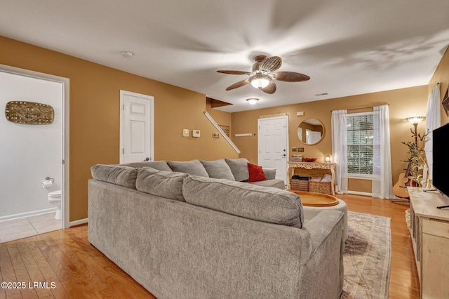 living room featuring a ceiling fan, light wood-type flooring, and baseboards