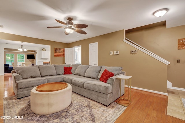 living area featuring visible vents, light wood-style flooring, baseboards, and ceiling fan