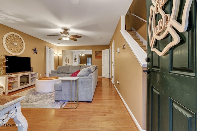 living room featuring stairway, a ceiling fan, light wood-type flooring, and baseboards